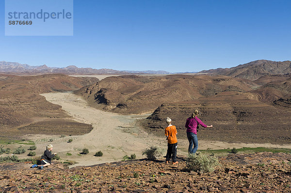 Vater und Sohn beim Steine-Weitwerfen  Blick über den Oranje Fluss von einem Aussichtpunkt in Aussenkehr  Namibia  Afrika
