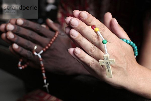 Mann und Frau beten zusammen mit Rosenkränzen in einer Kirche  Cotonou  Benin  Westafrika  Afrika