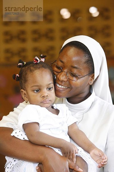 Franziskaner Schwester hält ein Waisenkind in Kinderkrippe und Kindergarten Ausführen von katholischen Nonnen  Lome  Togo  Westafrika  Afrika