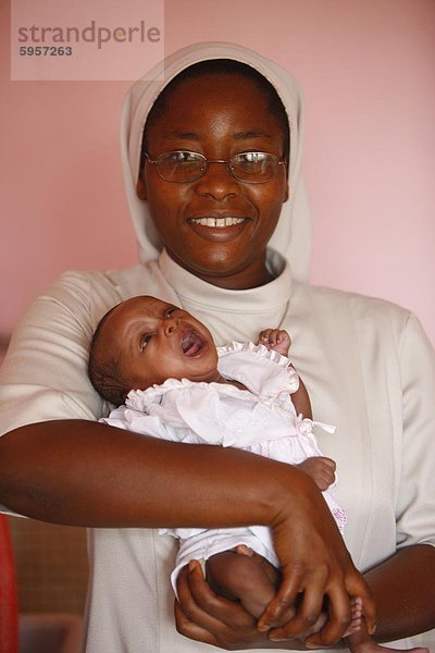 Franziskaner Schwester hält ein Waisenkind in Kinderkrippe und Kindergarten Ausführen von katholischen Nonnen  Lome  Togo  Westafrika  Afrika