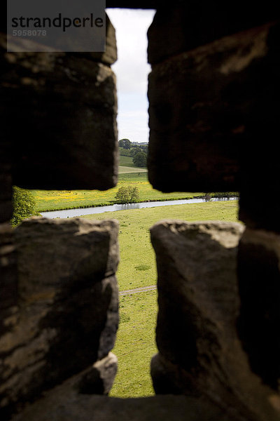 Fluß Aln gesehen durch Pfeil Schlitz der Mauern von Schloss Alnwick  Northumberland  England  Vereinigtes Königreich  Europa