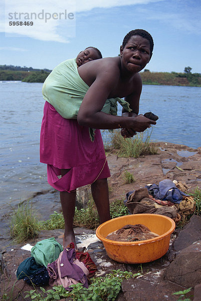 Kind schläft auf der Mutter zurück  als sie Kleidung  Uganda  Ostafrika  Afrika wäscht