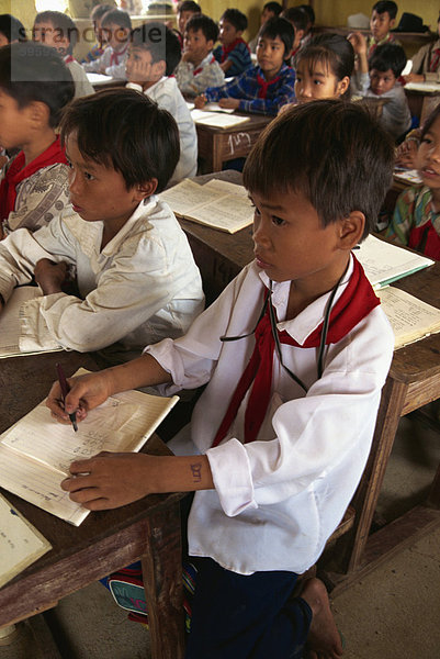 Porträt der Kinder in Schuluniform sitzen am Schreibtisch in einem Klassenzimmer in Nord-Vietnam  Indochina  Südostasien  Asien