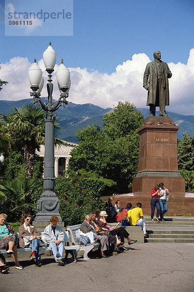 Menschen sitzen auf Bänken in der Nähe von Statue von Lenin in Yalta  die Krim  Ukraine  Europa
