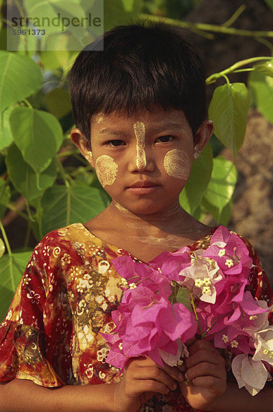 Kopf und Schultern Mädchenbildnis junge burmesische mit kurzen Haaren und Sandelholz Thanaka Gesichts Dekoration  halten einen Blumenstrauß  Bagan (Pagan) Bereich  Myanmar (Birma)  Asien