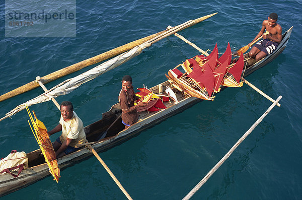 Männer in Ausleger-Kanus Modellbooten mit roten Segeln  Nosy Be  Madagaskar  Afrika zu verkaufen