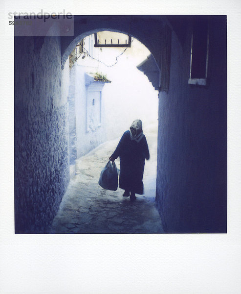 Frau in semi-silhouette Wandern durch Torbogen  Chechaouen  Marokko  Nordafrika  Afrika