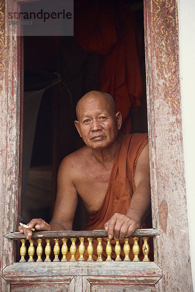 Kopf und Schultern Porträt eines älteren buddhistischer Mönch sitzt am Fenster in Luang Prabang  Laos  Indochina  Südostasien  Asien