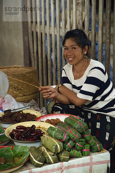 Porträt einer jungen laotische Frau lächelnd und Blick auf die Kamera  Verkauf von Essen in einem Straßenmarkt in Luang Prabang in Laos  Indochina  Südostasien  Asien