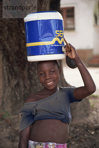 Portrait eines Mädchens tragen von Wasser auf dem Kopf  lächelnd und Blick auf die Kamera  Mosambik  Afrika