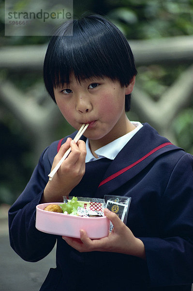 Schulmädchen Essen ihr Mittagessen mit Hacken klebt  Japan  Asien