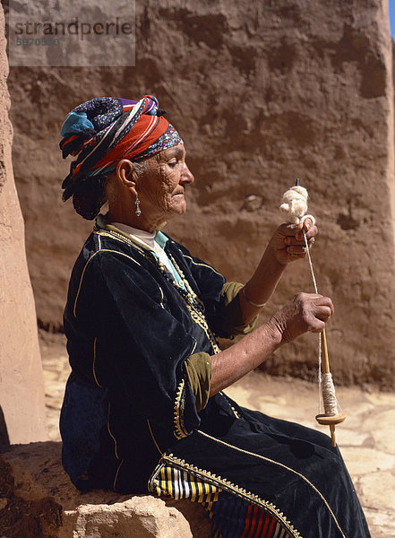 Alte Frau in traditioneller Kleidung  demonstriert wolle Spinnen  indem Spinnrocken  in der Nähe von Ouarzazate  Marokko  Nordafrika  Afrika