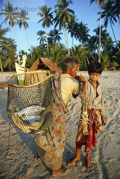 Fischer mit Weidenkorb und junge mit Muscheln  ihren Fang Morgen an Kemamaiy  Ost-Malaysia  Südostasien  Asien