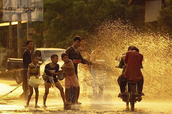 Menschen auf einem Motorrad wird mit Wasser überschüttet  von Männern und jungen während des Songklan-Festivals in Thailand  Südostasien  Asien