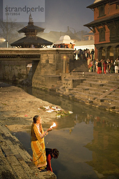 Zwei Frauen darbringen (Puja) vor der Morgendämmerung am Fluss Bagmati außerhalb der Shiva-Tempel während der Hindu-fest Shivaratri  Pashupatinath  Kathmandu  Nepal  Asien