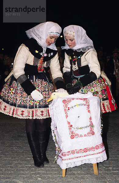 Zwei Mädchen in traditioneller Kleidung beruhigend Ente während der Interdue des Kampfes um die Ente  Martin fest mit Kranz und Ente Festival  Stadt Kyjov  Brnensko  Tschechische Republik  Europa