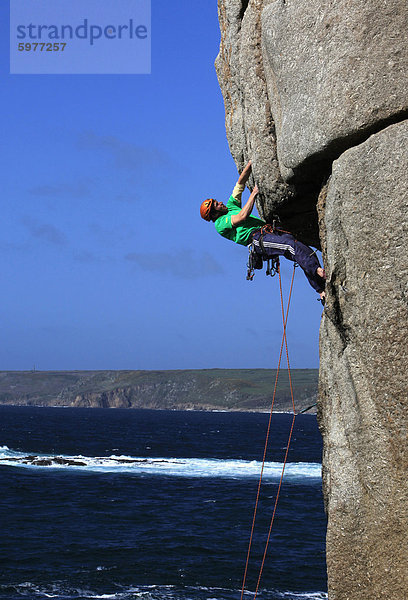 Ein Kletterer befasst sich einen schwierigen Überhang auf den Klippen in der Nähe von Sennen Cove  eine bekannte Rock Klettergebiet bei Lands End  Cornwall  England  Großbritannien  Europa