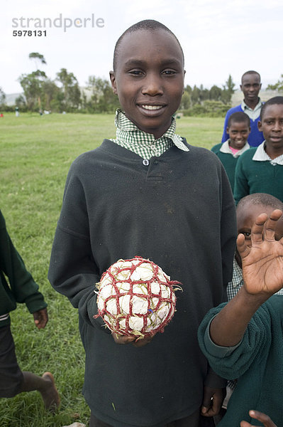 Schüler in Schuluniform halten Fußball hergestellt aus Plastiktüten und String  Ngeteti Primary School  Rift Valley in Kenia  Ostafrika  Afrika