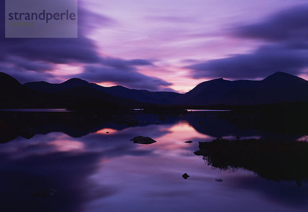 Spiegelungen im See Sonnenuntergang über dunklen Hügel von Rannoch Moor in der Hochlandregion in Schottland  Vereinigtes Königreich  Europa