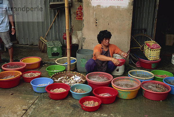 Frau hockt auf dem Bürgersteig  Verkauf von Fisch aus Kunststoff Schalen in der Fischmarkt am Taio auf Lantau Island  Hong Kong  China  Asien