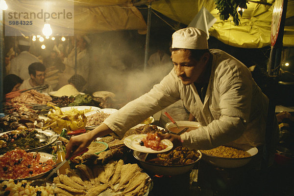 Porträt eines Mannes mit Essen aus seinem Stand auf dem Markt Djemaa el Fna in Marrakesch  Marokko  Nordafrika  Afrika