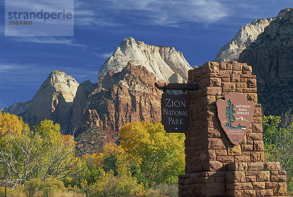 Schild am südlichen Eingang zum Park  Bäume in Herbstfarben und der Berg der Sonne und die Zwillingsbrüder Gipfel  in den Zion National Park  Utah  Vereinigte Staaten von Amerika  Nordamerika