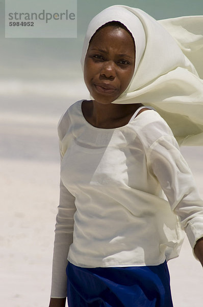 Ein Schulmädchen entlang Kiwendwa Strand trägt einen weißen Kopftuch und blauen Rock  Sansibar  Tansania  Ostafrika  Afrika