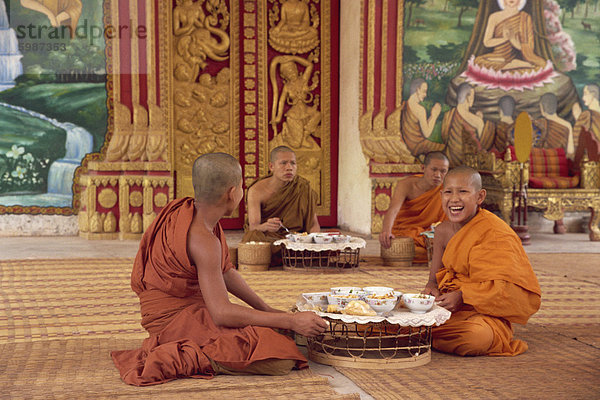 Eine Gruppe von buddhistischen Mönchen in Safran Roben auf dem Fußboden  Essen  am Wat Chan in Vientiane  Laos  Indochina  Südostasien  Asien