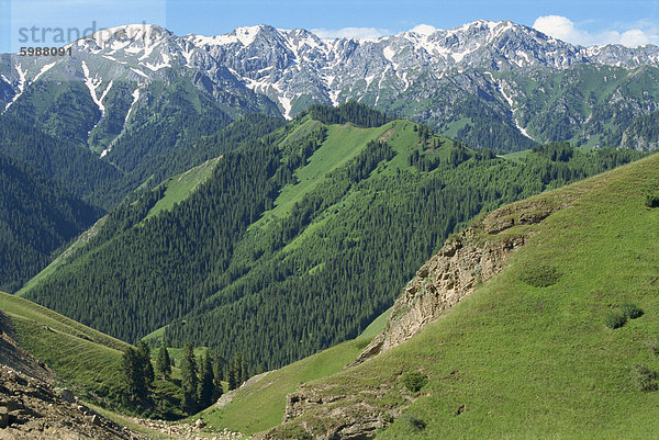 Bewaldete Hügel und Schnee bedeckten Berge am Tianshan Sayram See in Xinjiang  China  Asien