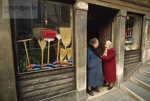 Zwei alte Damen sprechen in der Tür ein Besen-Geschäft in Venedig  Veneto  Italien  Europa