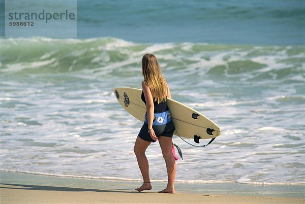 Mädchen tragen Surfbrett am Strand  Byron Bay  New South Wales  Australien  Pazifik