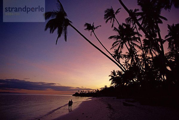 Paar und Palmen Bäume am Alona Beach silhouetted bei Sonnenuntergang auf der Insel Panglao  vor der Küste von Bohol  Philippinen  Südostasien  Asien