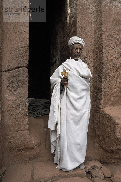 Ein Priester steht am Eingang zu den Felskirchen Kirche von Bet Gabriel-Rufael  in Lalibela  Äthiopien  Afrika