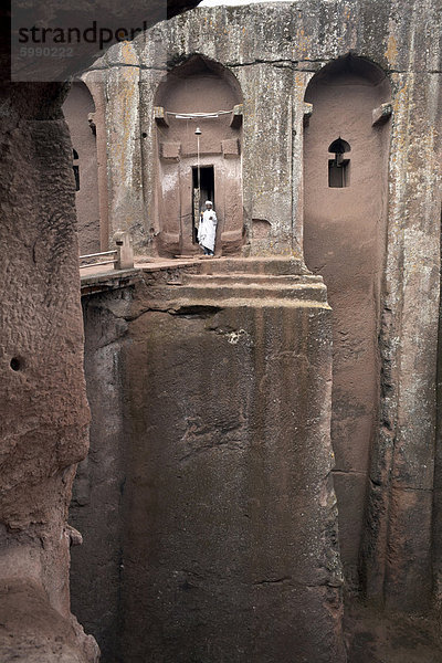 Ein Priester steht am Eingang zu den Felskirchen Kirche von Bet Gabriel-Rufael  in Lalibela  UNESCO-Weltkulturerbe  Äthiopien  Afrika