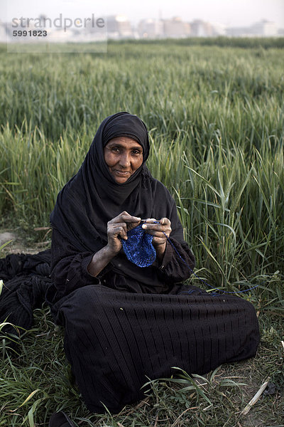 Eine Frau sitzt in einem Feld auf der Luxor Westbank  Ägypten  Nordafrika  Afrika stricken