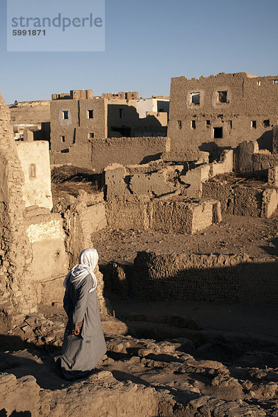 Ein Mann hebt sich die Ruine der Stadt Lehmziegeln Al-Qasr  Oase Dakhla  Ägypten  Nordafrika  Afrika