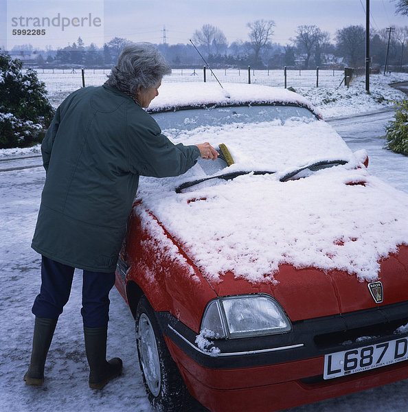 Frau kratzen Schnee von der Windschutzscheibe eines Autos im Winter  Deutschland  Europa