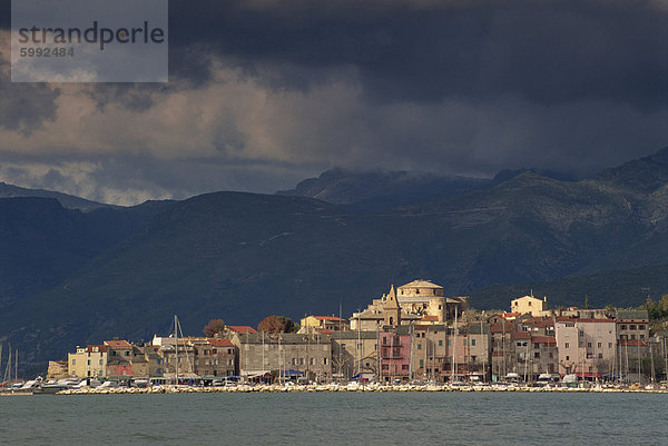 Dunkle Wolken über Hügel und die Skyline der Stadt von St. Florent am Cap Corse auf Korsika  Frankreich  Mittelmeer  Europa