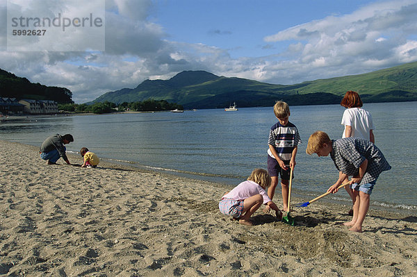 Eine kleine Gruppe von Kindern Graben am Strand von der See  Loch Lomond  Trossachs  Schottland  Vereinigtes Königreich  Europa