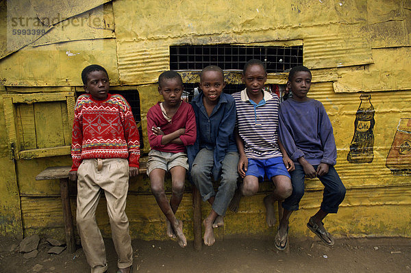 Porträt einer Gruppe von fünf jungen  Slum-Kinder  sitzen auf einer Bank im Freien  in die Kamera schaut Kariobangi  Nairobi  Kenia  Ostafrika  Afrika