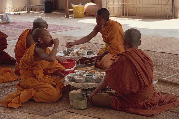 Eine Gruppe von buddhistischen Mönchen in Safran Roben auf dem Fußboden  Essen  am Wat Chan in Vientiane  Laos  Indochina  Südostasien  Asien