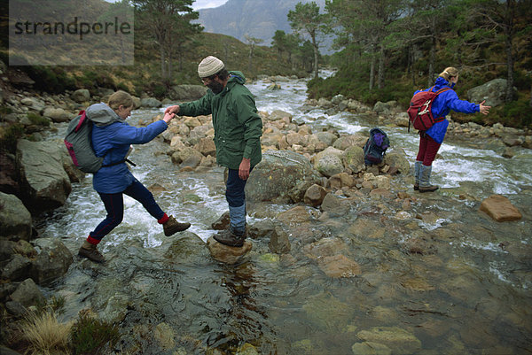 Wanderer über Fluss in den Ben-Damph Hügeln  in der Nähe von Loch Torridan  Highlands  Schottland  Vereinigtes Königreich  Europa