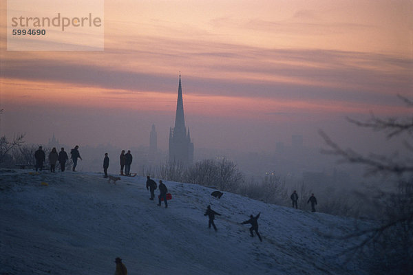 Menschen in einer Winterlandschaft mit Schnee auf dem Boden und Norwich Kathedrale im Hintergrund  Norwich  Norfolk  England  Vereinigtes Königreich  Europa