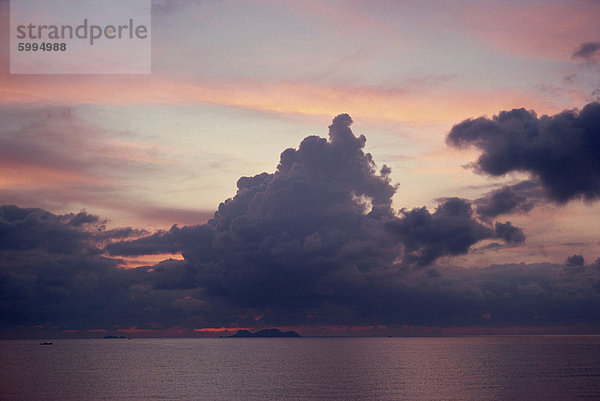 Hoch aufragenden dunklen grauen Wolken in einem rosa und blauen Himmel über dem Meer in Malaysia  Südostasien  Asien