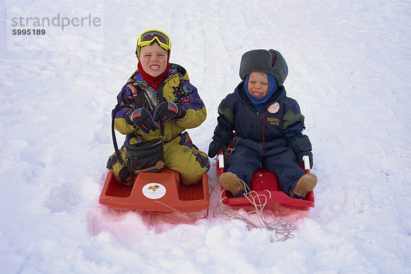 Zwei Kinder auf rot Schlitten im Schnee in Finnland  Skandinavien  Europa spielen