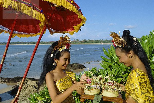 Zwei Frauen bereiten ein Angebot zum Meer am Jimbaran Strand auf der Insel Bali in Indonesien  Südostasien  Asien