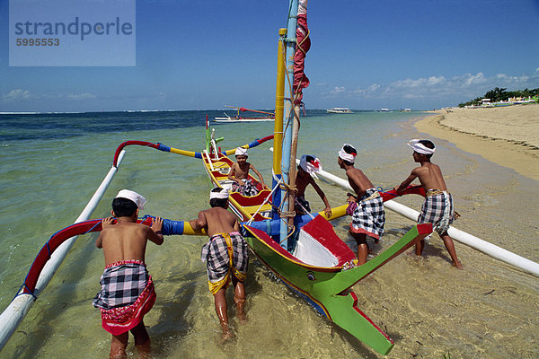 Männer  die Einleitung einer Fischerei Auslegerboot von Sanur Beach auf der Insel Bali in Indonesien  Südostasien  Asien