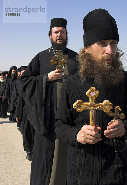 Priester in schwarz hält Olivenholz kreuzt in Prozession um den Fluss Jordan während Christian orthodoxe Zeremonie am Dreikönigstag  Qasr el Yahud  Israel  Naher Osten