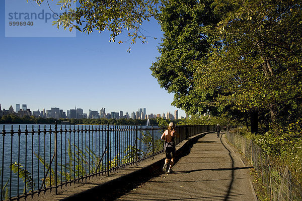Ein Jogger auf der Strecke rund um den Stausee im Central Park und die Skyline der Stadt in den Hintergrund  New York City  New York State  Vereinigten Staaten von Amerika  Nordamerika