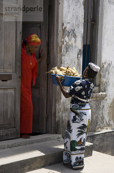 Eine Frau verkaufen Mais von Tür zu Tür auf einer Straße in Stone Town  Sansibar  Tansania  Ostafrika  Afrika